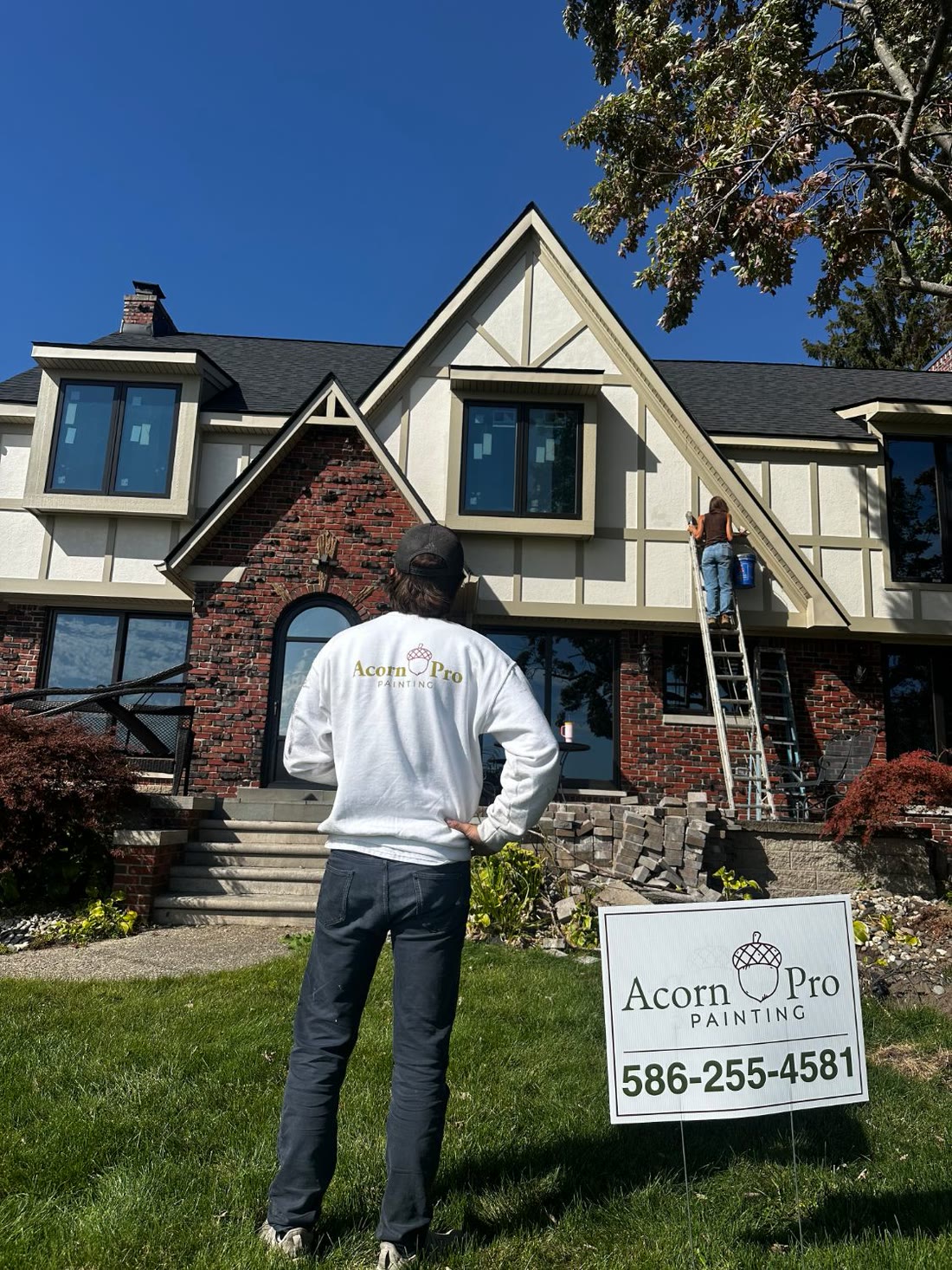 Acorn Pro Painting team members at work on a home, with an Acorn Pro yard sign on the front lawn