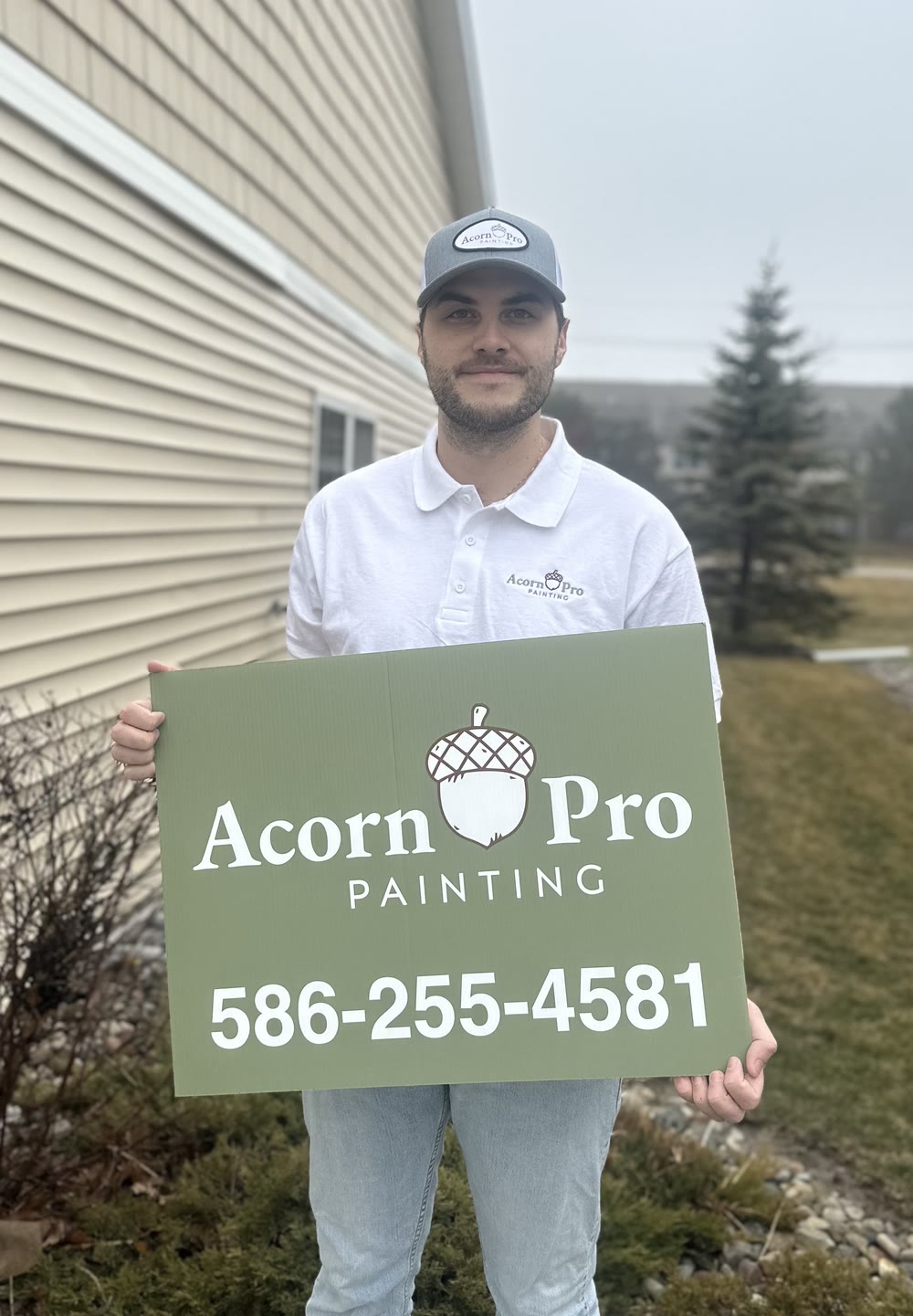 Michael Acorn holding an Acorn Pro Painting yard sign