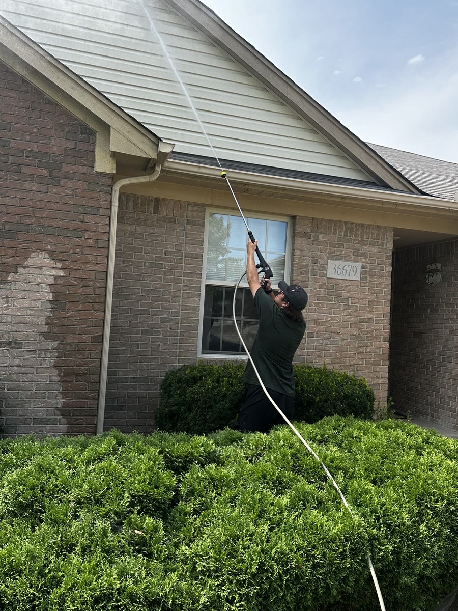 An Acorn Pro Painting team member pressure washing a home's siding