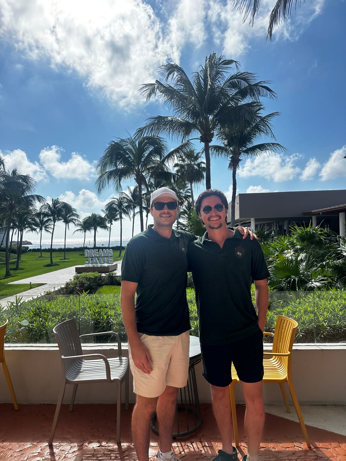 Two Acorn Pro Painting team members in company polos standing together in front of palm trees